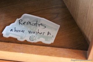 note on wooden shelf that camper tv remotes are in the house for the winter 