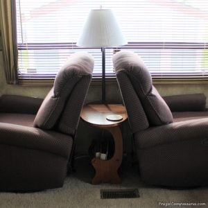 Wooden endtable nestled tightly between two recliners 